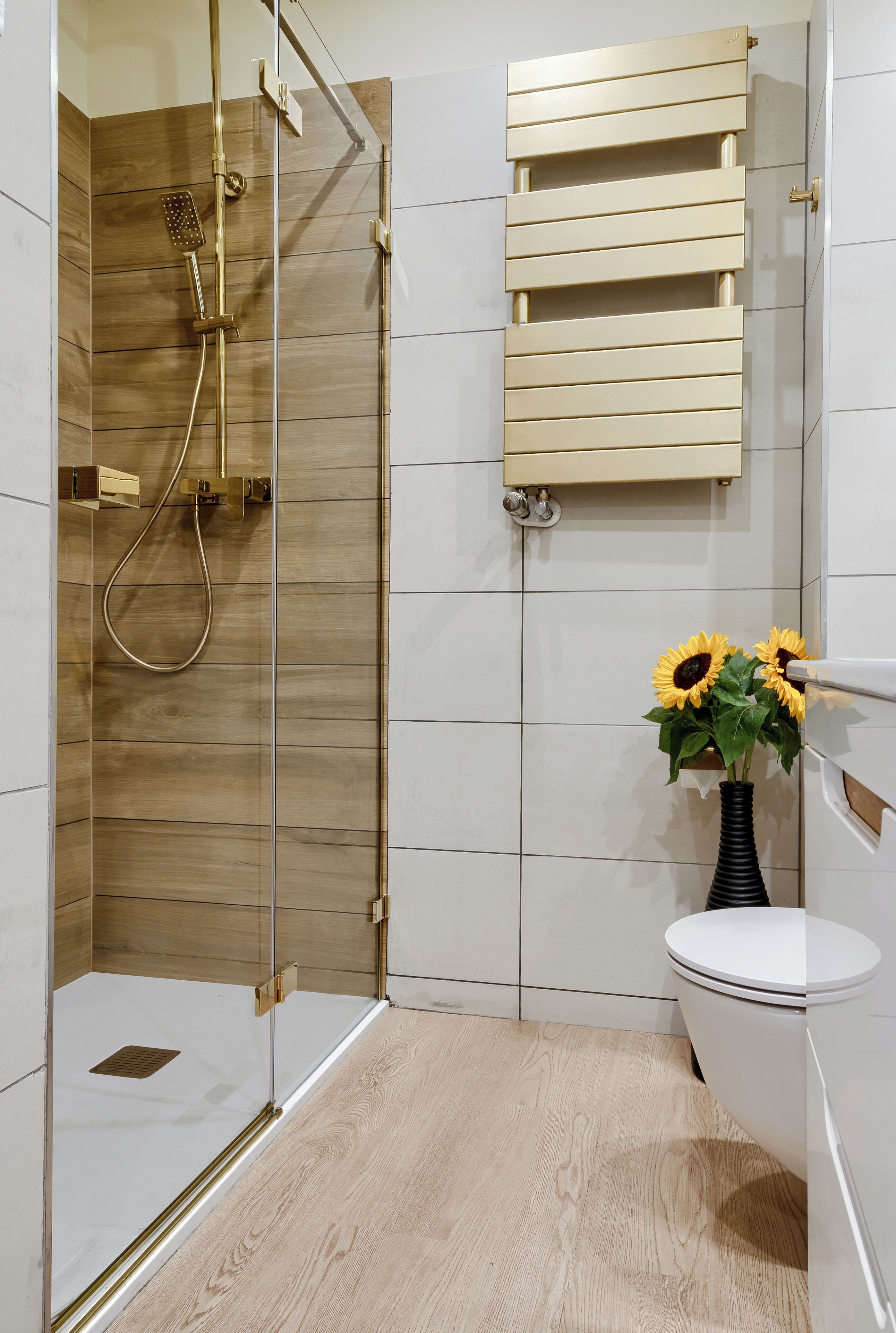 A modern bathroom with a glass-enclosed shower, a toilet, and a wooden vanity.