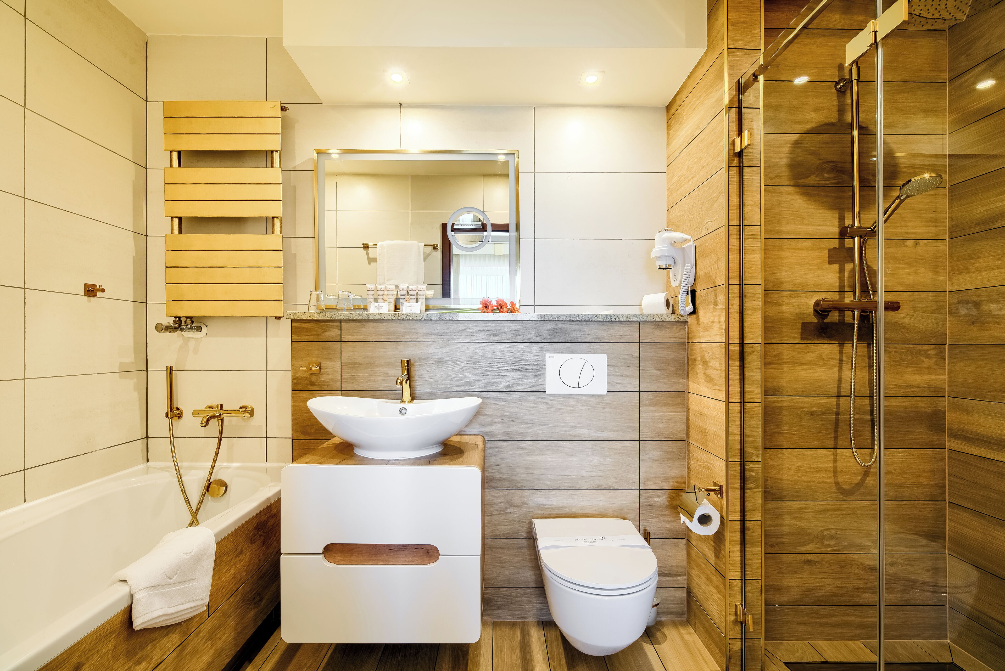 Un baño moderno con bañera, lavamanos, inodoro y cabina de ducha de madera.
