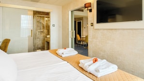 Habitación de hotel con cama, baño, televisión y zona de estar.