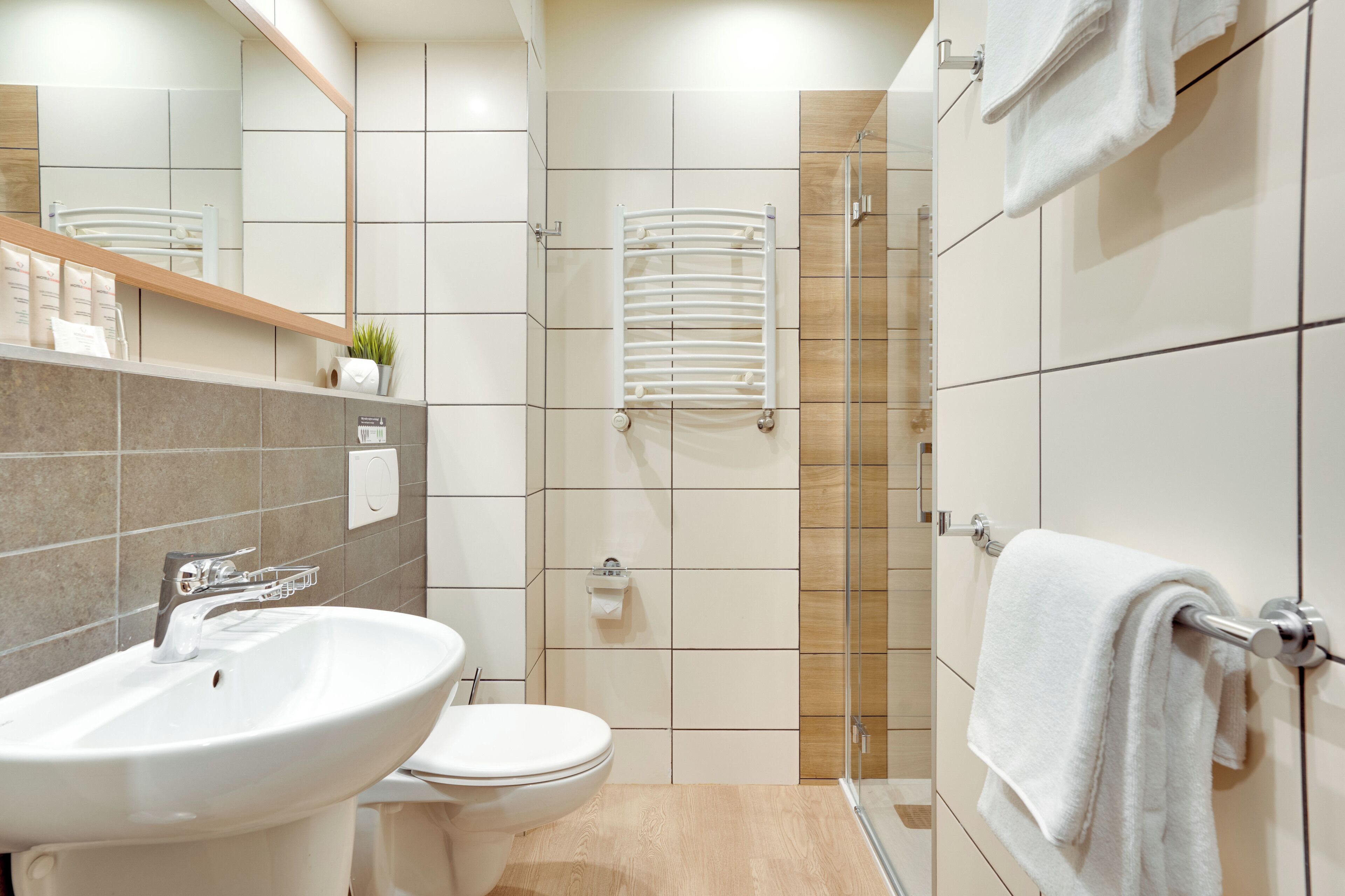 A modern bathroom with a sink, toilet, mirror, towel rack, and shower area.