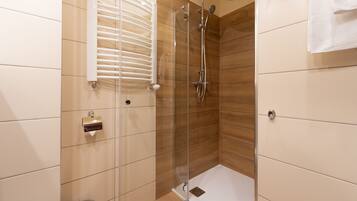 Un baño moderno con ducha de vidrio, inodoro y perchero para toallas.
