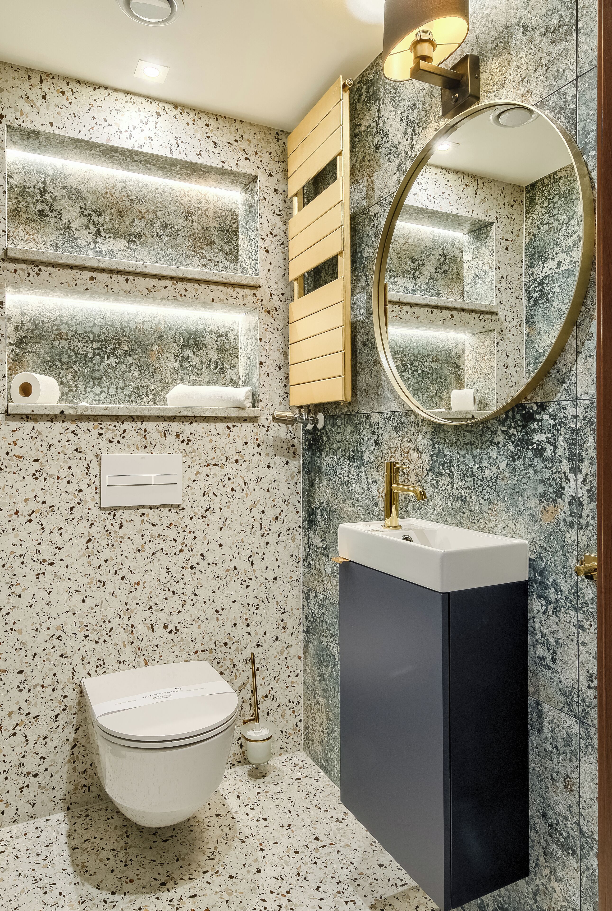 A bathroom with a freestanding toilet, a wall-mounted sink, a mirror, and a towel rack.