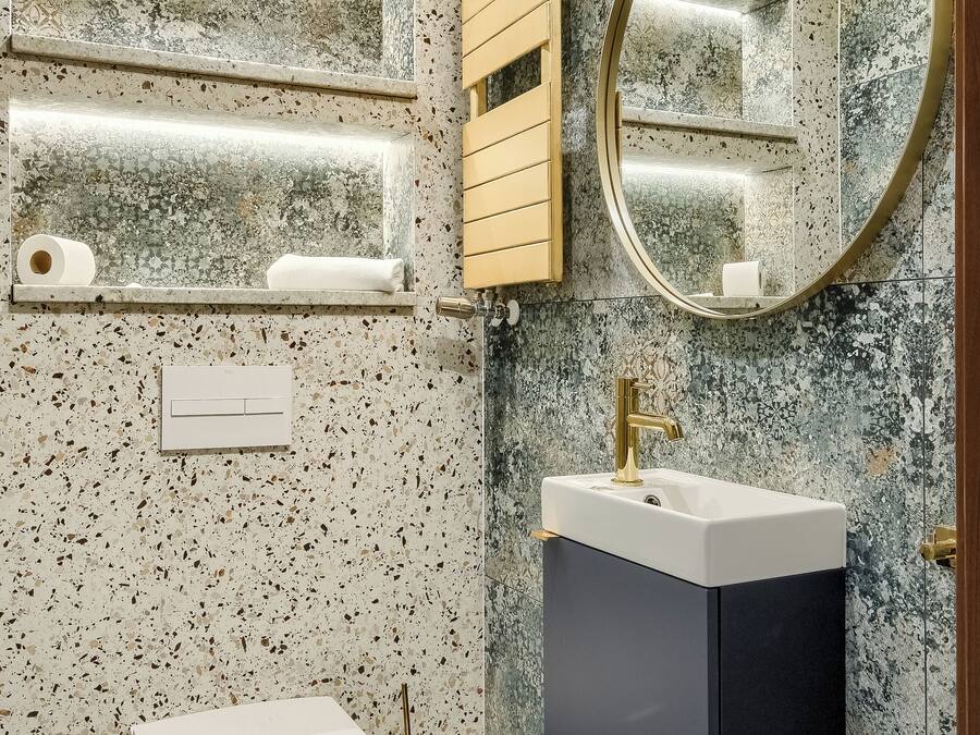 Ein Badezimmer mit freistehender Toilette, einem wandmontierten Waschbecken, einem Spiegel und einem Handtuchhalter.