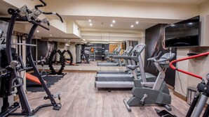 Un gimnasio moderno con cintas de correr, elípticas y máquinas de pesas.