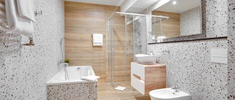Une salle de bain moderne avec une baignoire sur pieds, une douche à parois de verre, un lavabo et des toilettes.