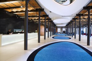 A spacious lobby with a modern design, featuring a reception desk, multiple seating areas, and a unique ceiling structure. - Vienna House by Wyndham Andel's Lodz (Lodz)