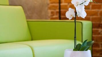 A green sofa with a white orchid in a white vase.