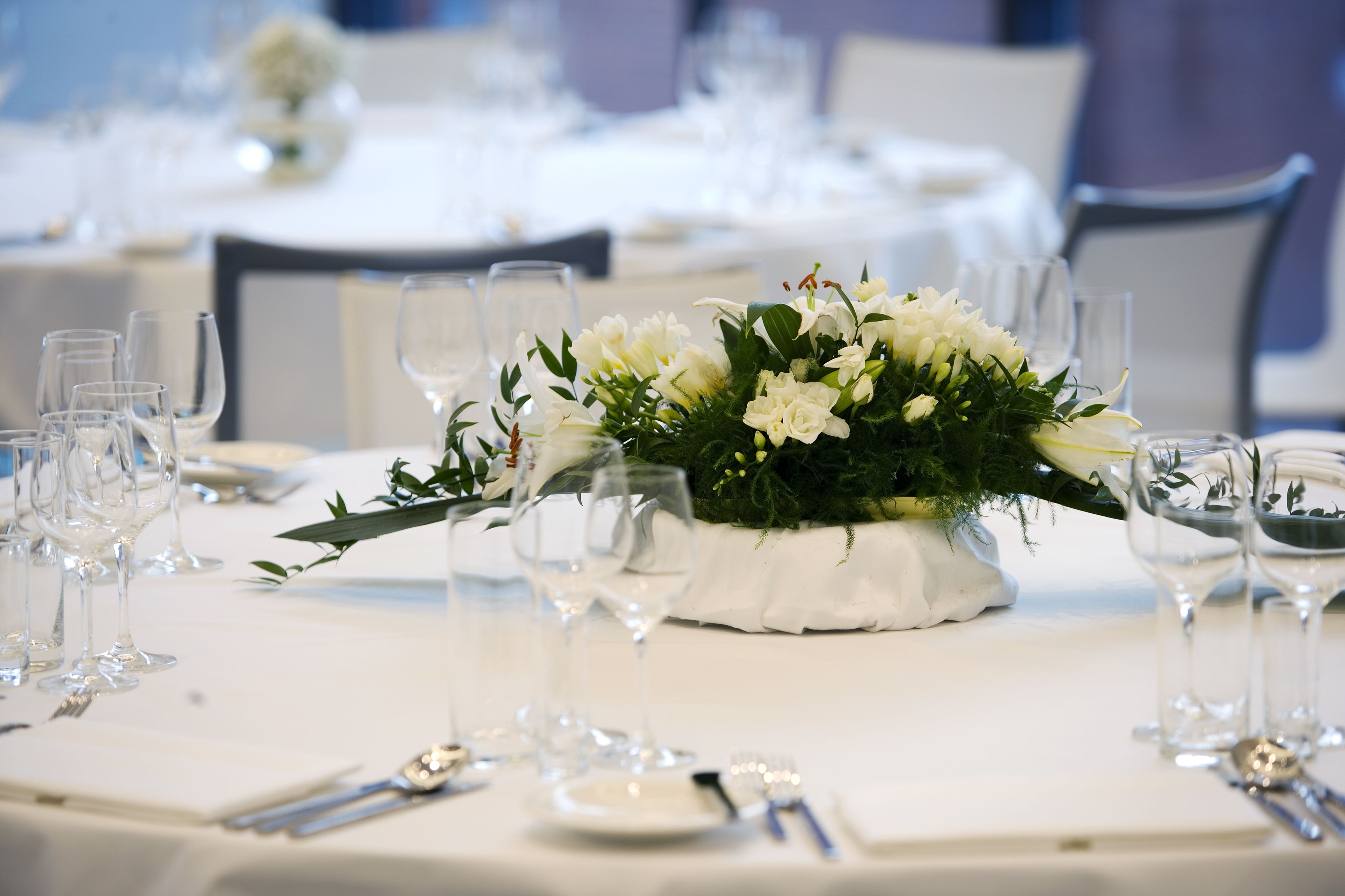A table set for a formal event with a centerpiece of white flowers and greenery.