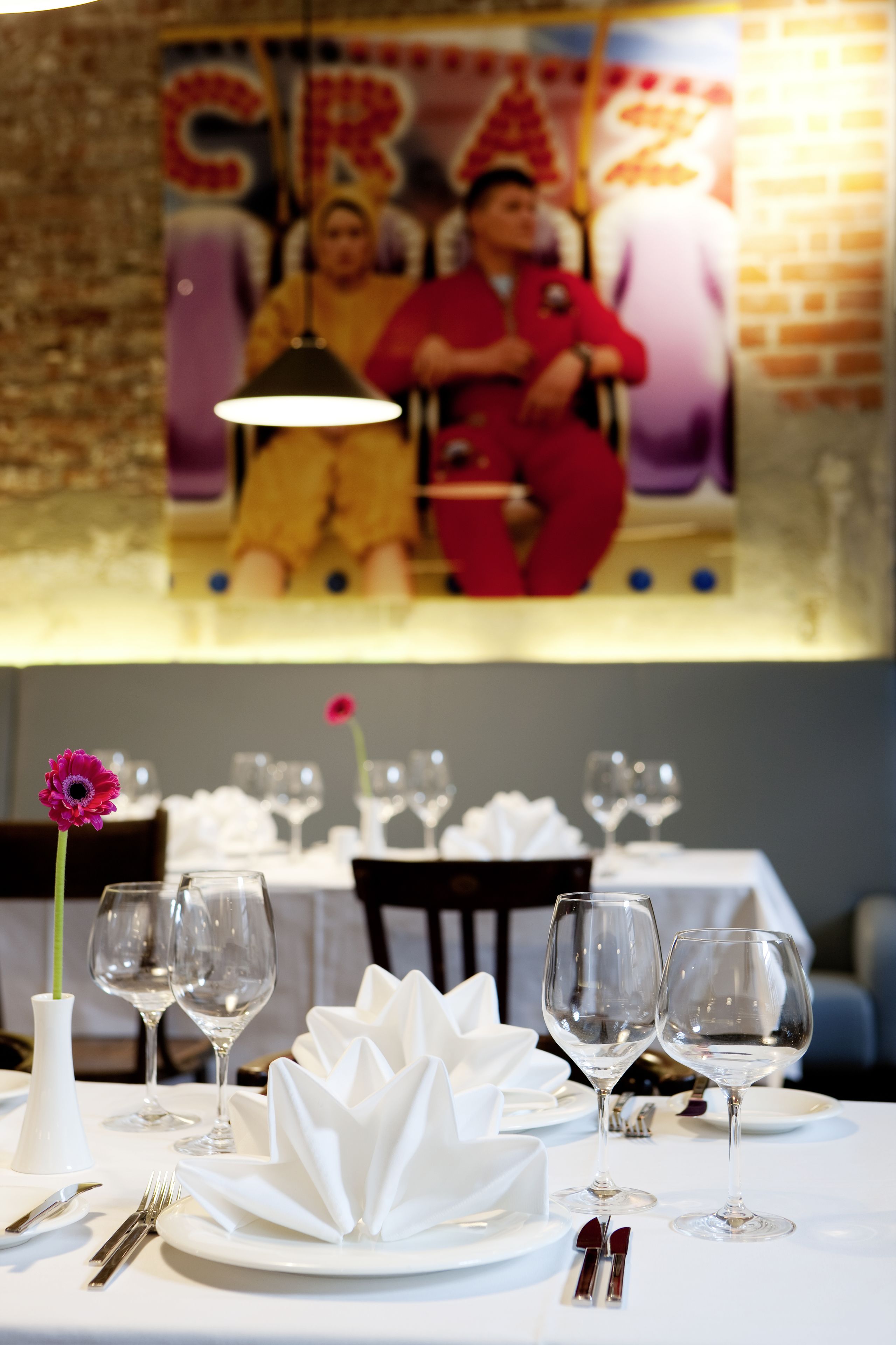 Une table à manger dressée avec de la vaisselle blanche et un vase contenant une seule fleur.