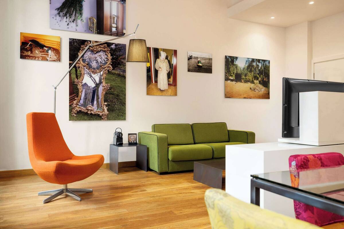 Una sala moderna con un sofá verde, un sillón naranja y un televisor de pantalla plana.
