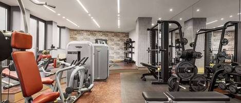 Un gimnasio moderno con varios equipos de ejercicio, una banca y un pared con diseño.