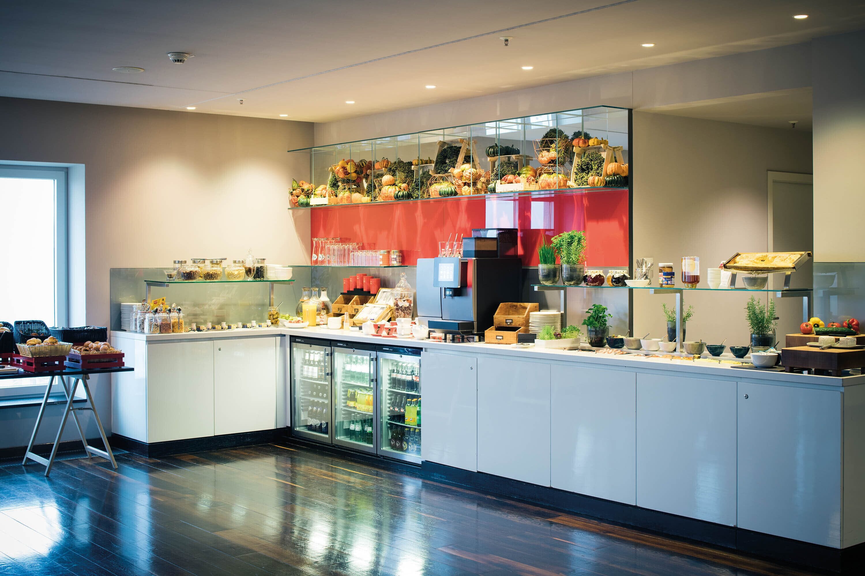 Een moderne keuken met een glazen displaykast, een koffieapparaat en een koelkast.