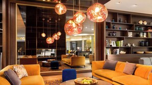 Una sala de estar moderna con sofás naranja, una mesa de centro y lámparas colgantes.