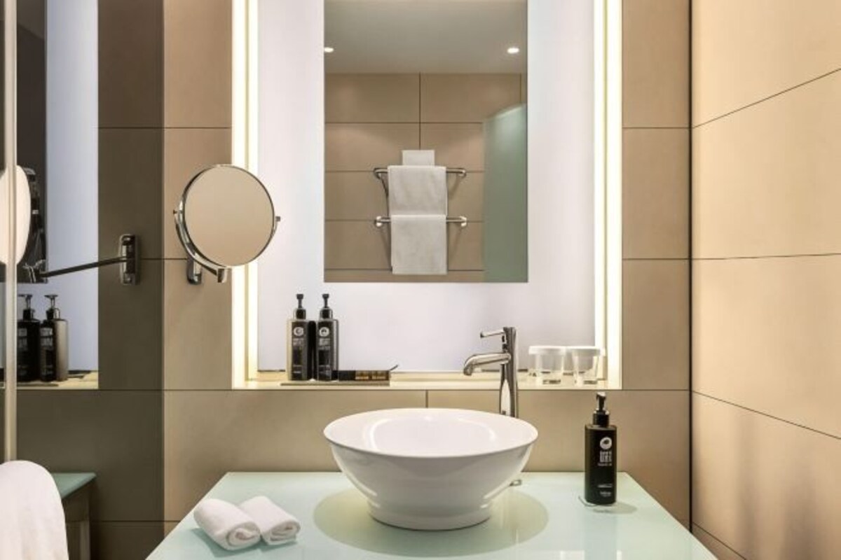 Un baño moderno con un lavamanos grande, un espejo y un perchero para toallas.