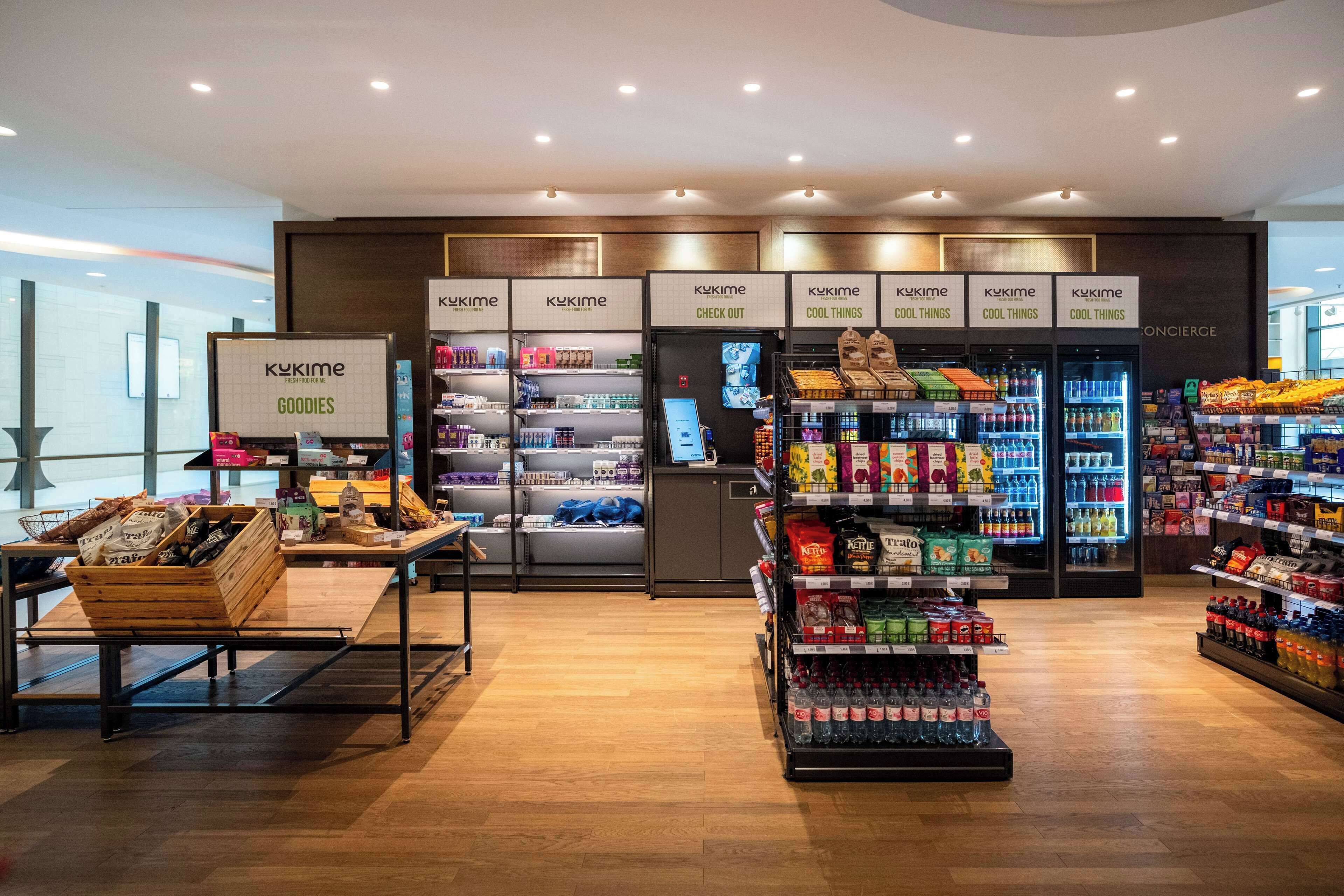 Interior moderno de un supermercado con secciones refrigeradas, una zona de cajas registradoras y una gran variedad de productos envasados en estantes.