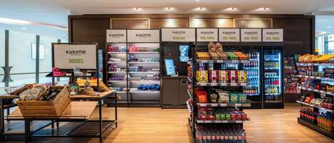 Interior moderno de un supermercado con secciones refrigeradas, una zona de cajas registradoras y una gran variedad de productos envasados en estantes.