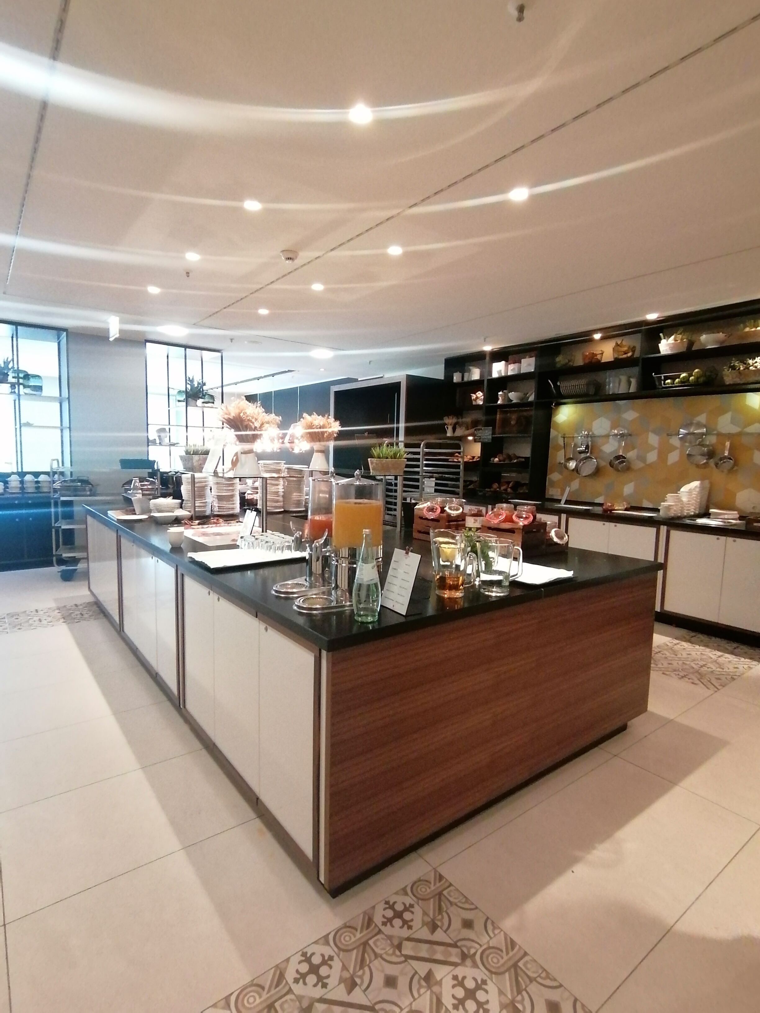 A modern kitchen with a central island, equipped with various appliances and a variety of food items.