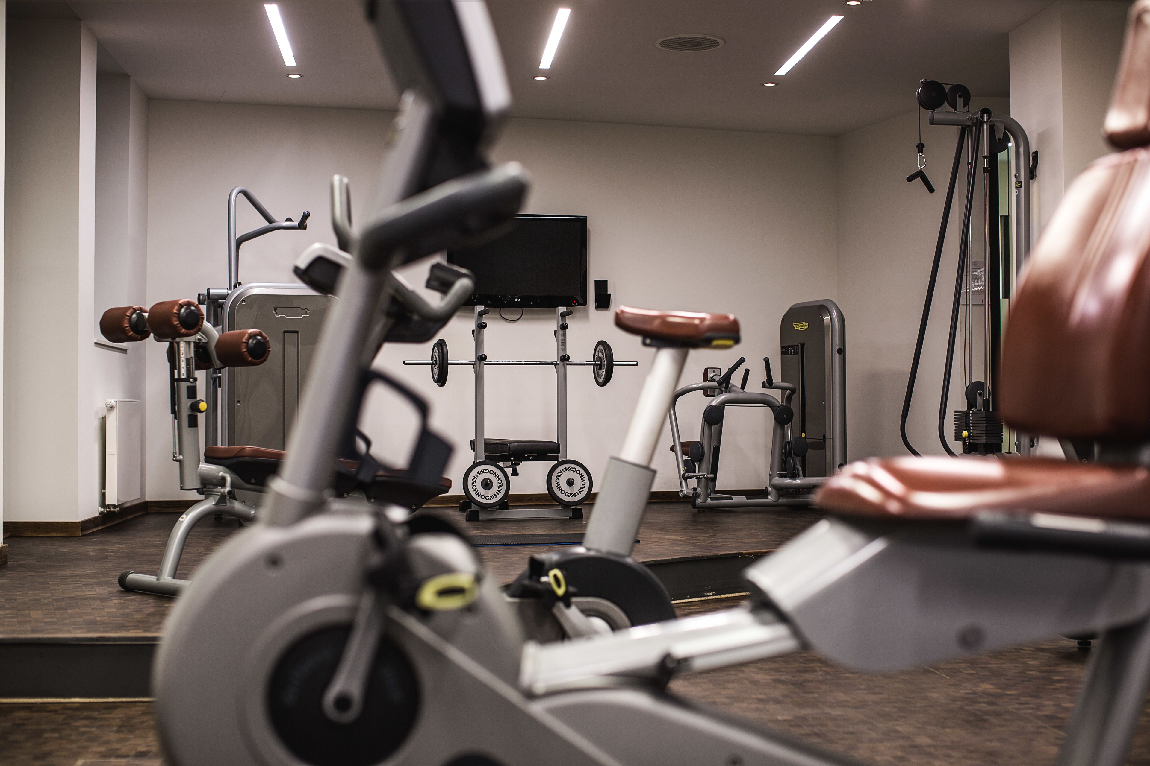 A gym with exercise equipment, a television, and a mirror.