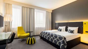 Una habitación de hotel con una cama, un escritorio, una silla y una lámpara.