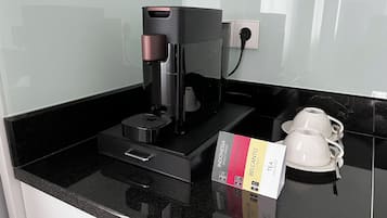 A coffee machine on a black countertop with a coffee pod holder and a box of assorted tea.