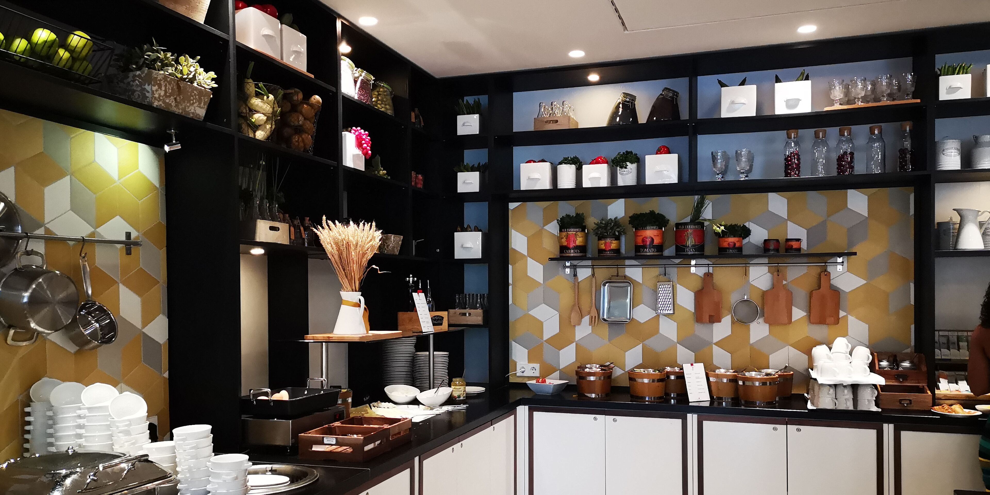 A well-organized kitchen with shelves stocked with various kitchenware, a display of food items, and neatly arranged utensils.
