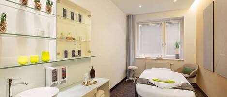 A modern bathroom with a glass shelf, a white sink, and a massage table.