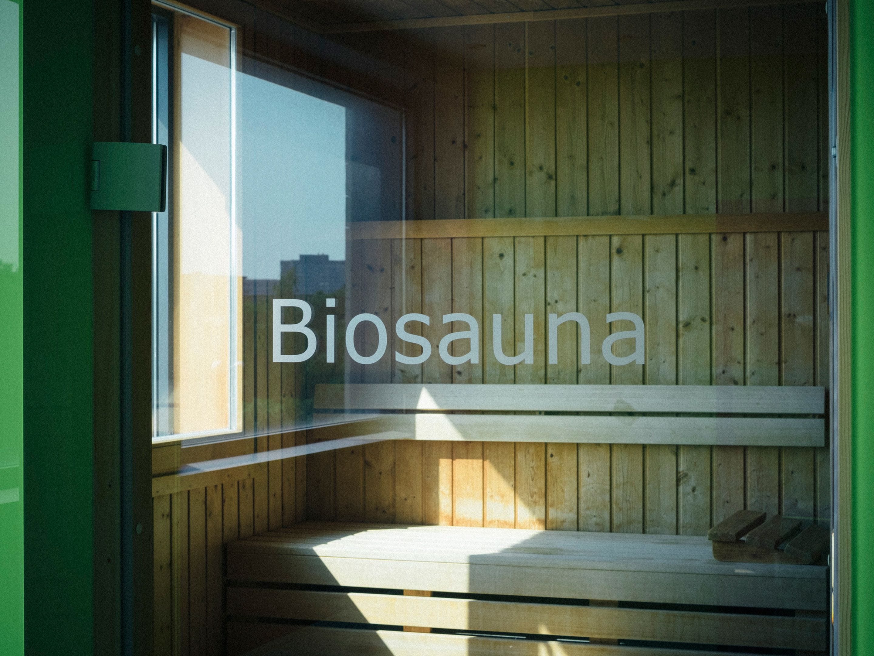 Una cabaña de madera con ventana y la palabra "Biosauna" en el vidrio.
