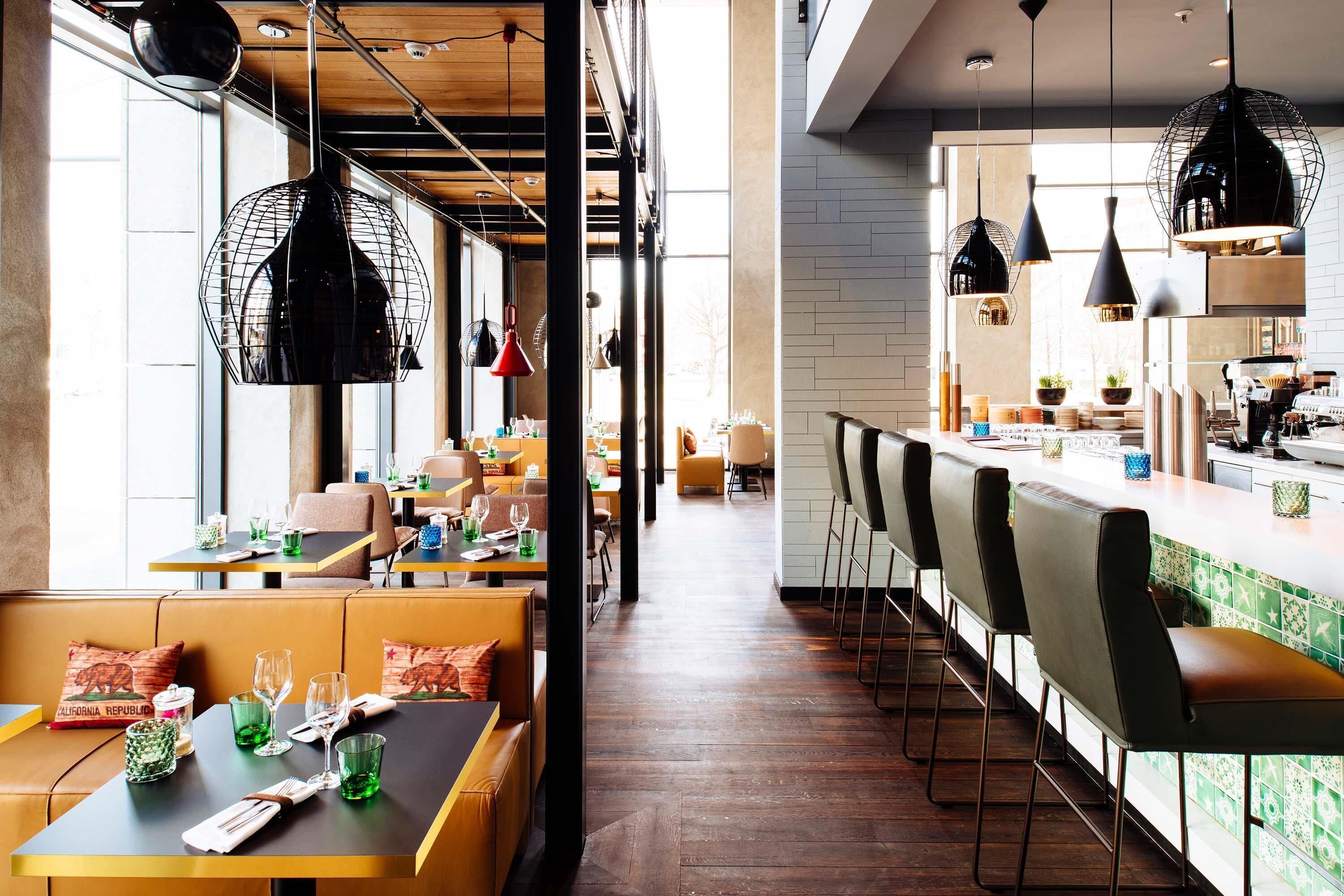 Un restaurant avec des banquettes, des tables hautes et un bar.