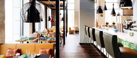 Un restaurante con cabinas, mesas altas y una zona de bar.