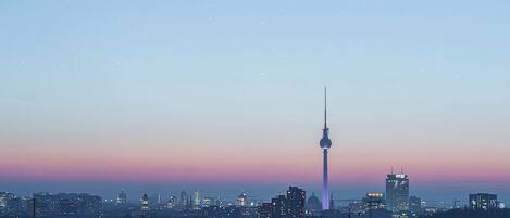 Un paisaje urbano al atardecer con una torre destacada y un efecto de larga exposición del tráfico en movimiento.