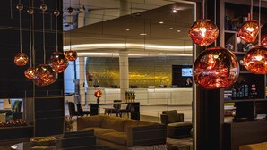 Un moderno vestíbulo de hotel con sofás, una recepción y lámparas decorativas colgantes.
