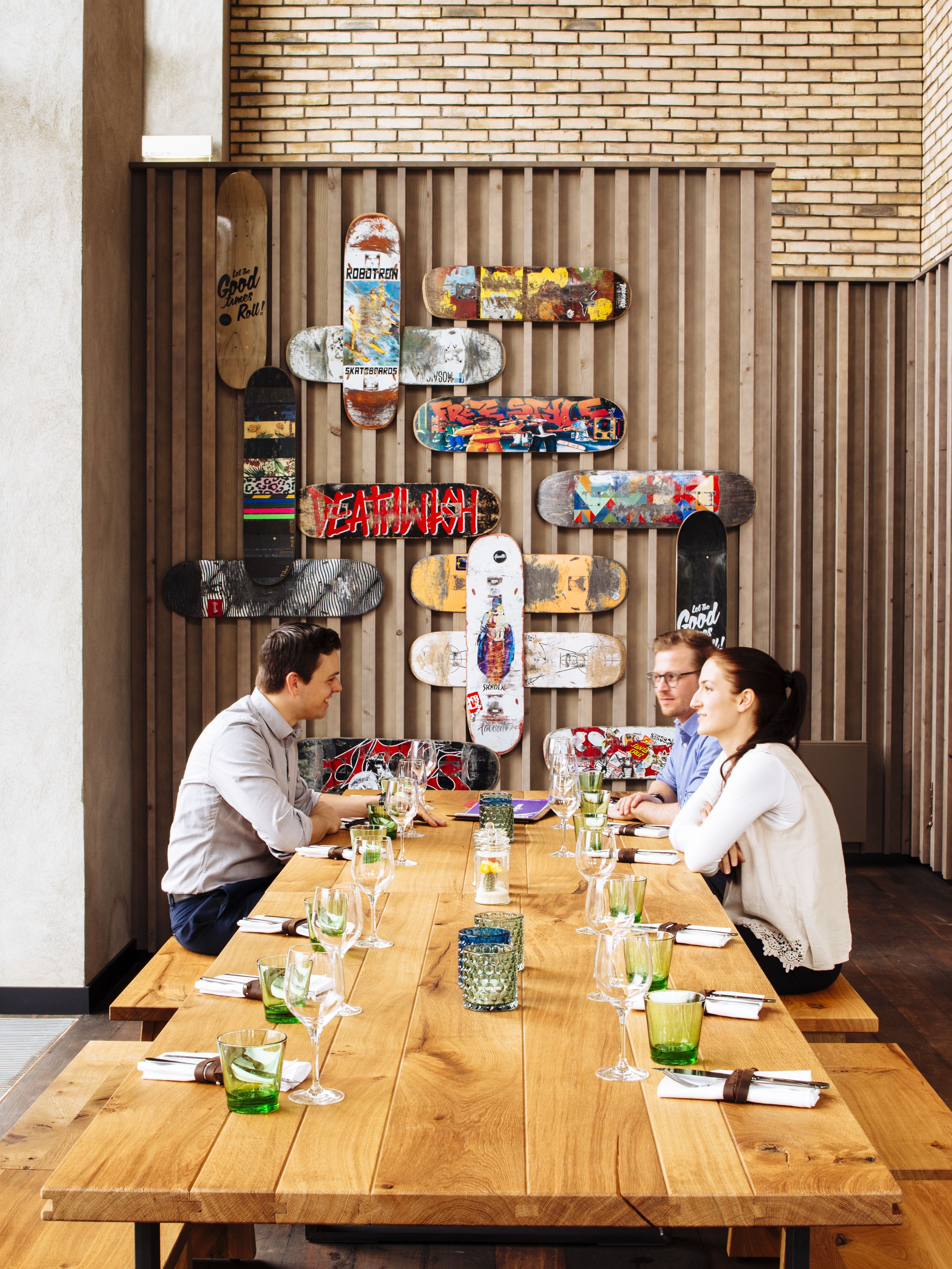 A dining area with a wooden table set for four, surrounded by skateboard art on the wall.