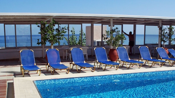 A swimming pool with blue water, surrounded by blue lounge chairs and potted plants. - Achillion Palace Hotel Rethymno City Center (Rethymno)