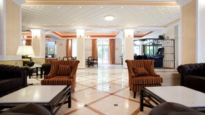 A spacious lobby with a tiled floor, striped armchairs, a piano, and a seating area with sofas and tables. - Achillion Palace Hotel Rethymno City Center (Rethymno)