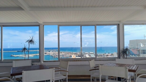 Una habitación con vistas al mar, muebles blancos y ventanas amplias.