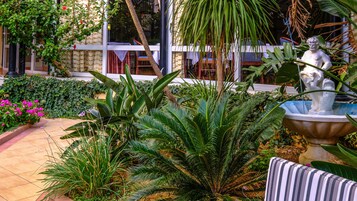 A garden with a statue, various plants, and a tiled pathway.