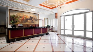 A hotel lobby with a reception desk, a large painting, and a chandelier. - Achillion Palace Hotel Rethymno City Center (Rethymno)