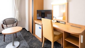 Une chambre d’hôtel équipée d’un bureau, d’une chaise, d’une télévision et d’un petit réfrigérateur.