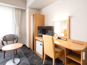 Habitación de hotel con escritorio, silla, televisión y un refrigerador pequeño.