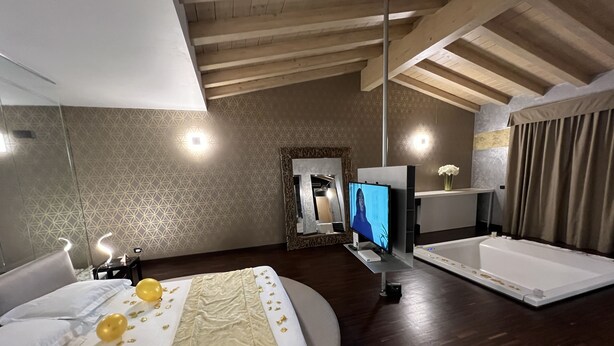 Een moderne slaapkamer met een groot bed, een televisie, een badkuip en een spiegel.