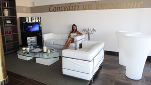 Een moderne woonkamer met een witte bank, een glazen salontafel en een flatscreen televisie.