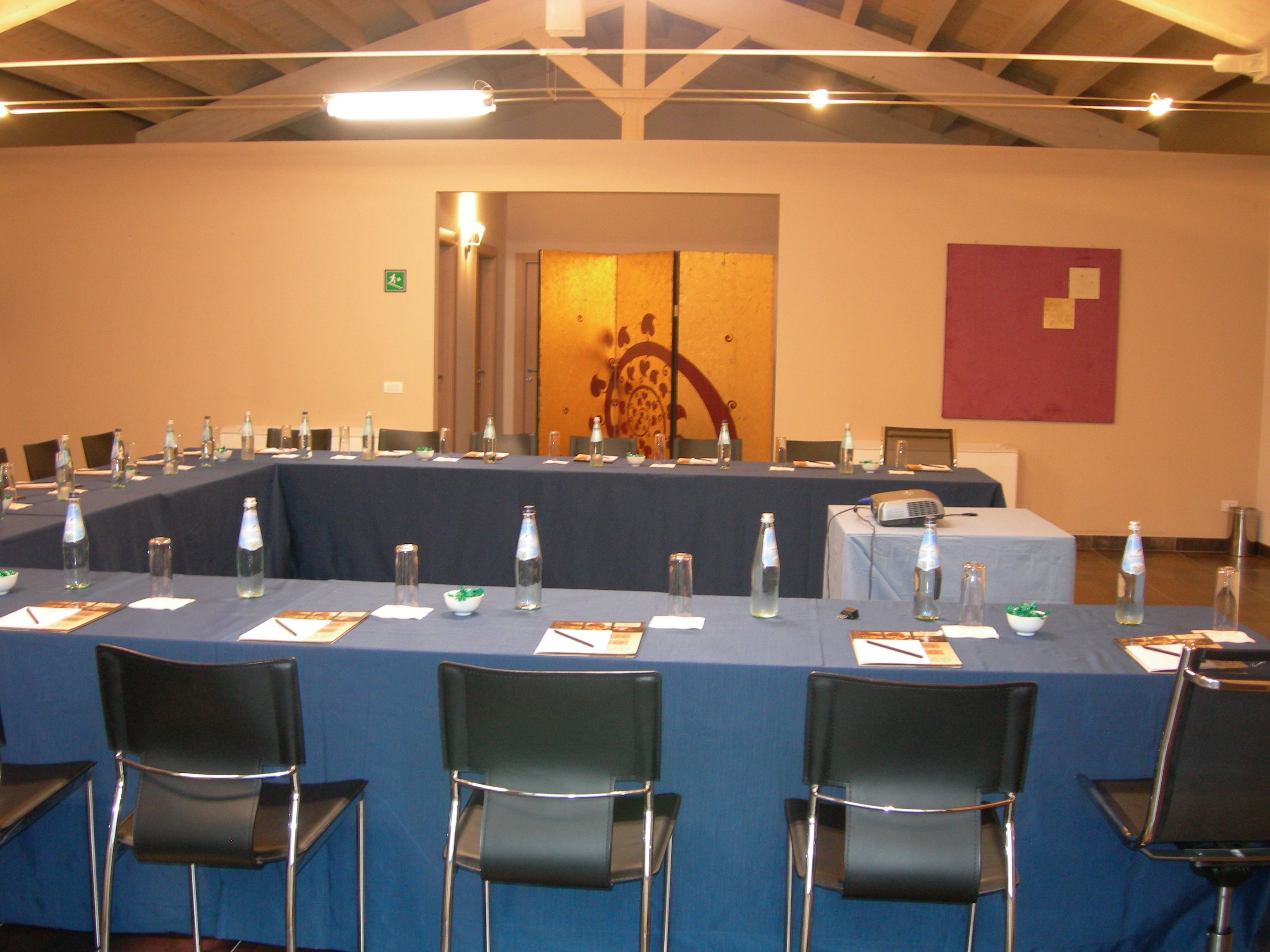 A conference room with a long table set for a meeting, equipped with chairs, water bottles, and a projector.
