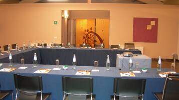 A conference room with a long table set for a meeting, equipped with chairs, water bottles, and a projector.