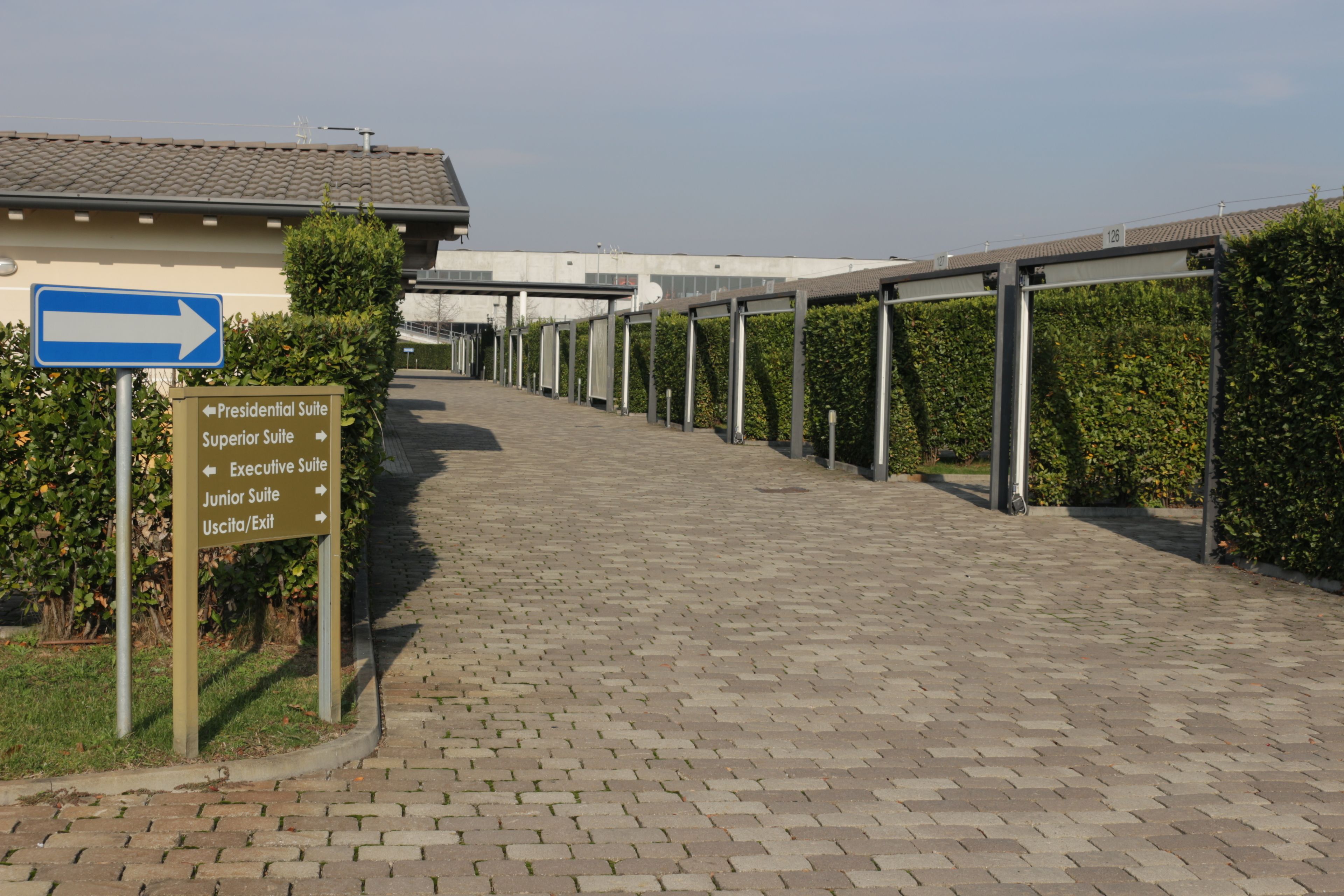 A pathway leading to a building with directional signs indicating various suites and exits.