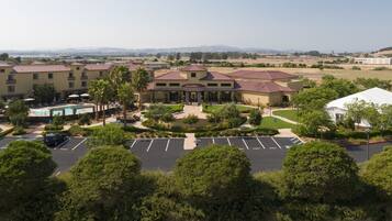 A hotel with a pool, outdoor seating, and a parking lot.