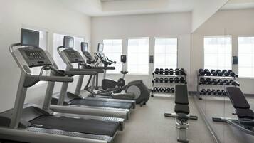 A gym with treadmills, an elliptical, and a bench press.