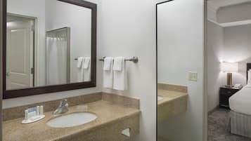 A bathroom with a granite countertop sink, a mirror, and a towel rack.