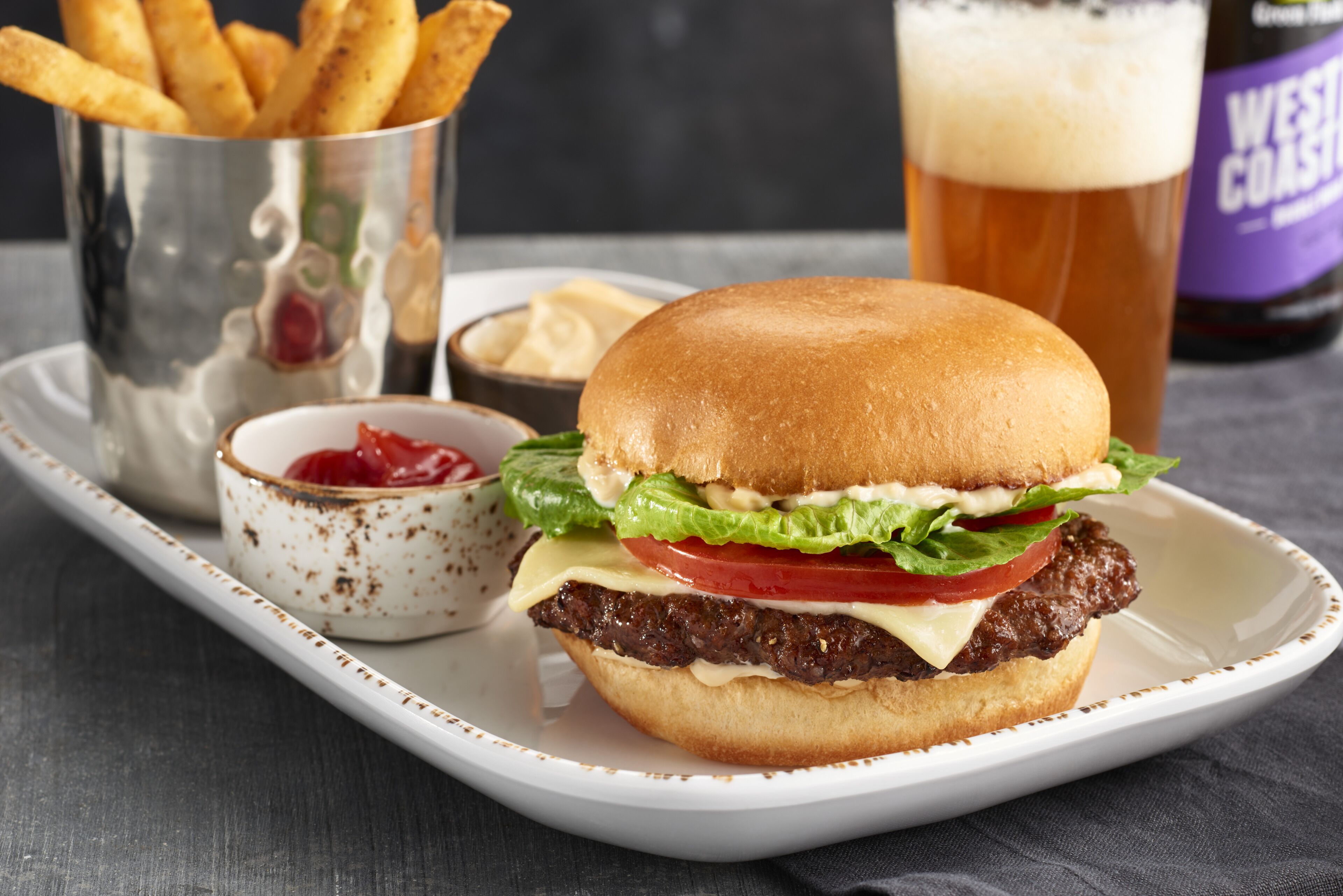 A burger with fries and a drink on a tray.