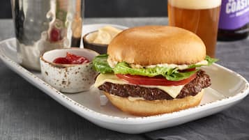A burger with fries and a drink on a tray.