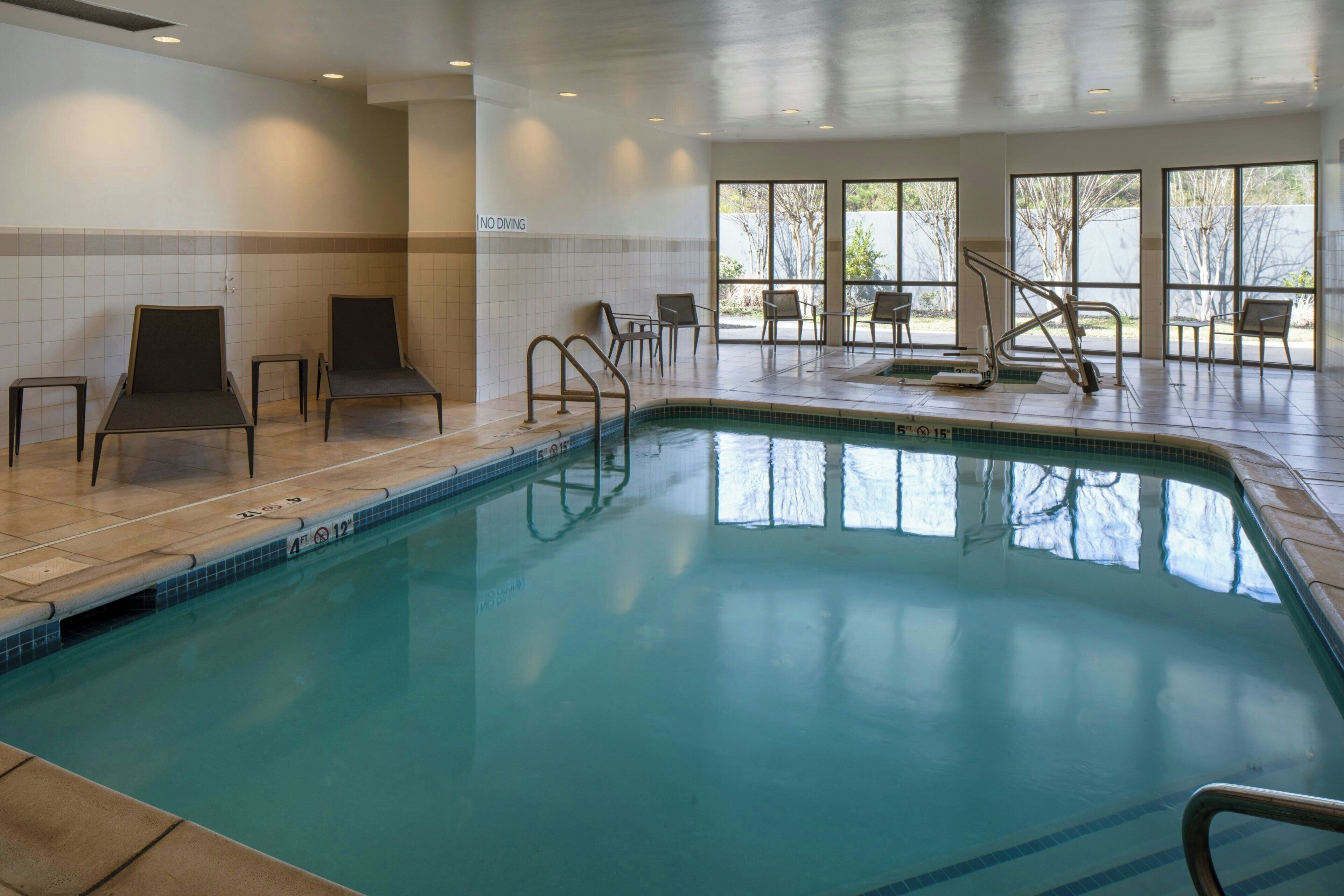 An indoor swimming pool with clear water, surrounded by lounge chairs and a 'NO DIVING' sign.